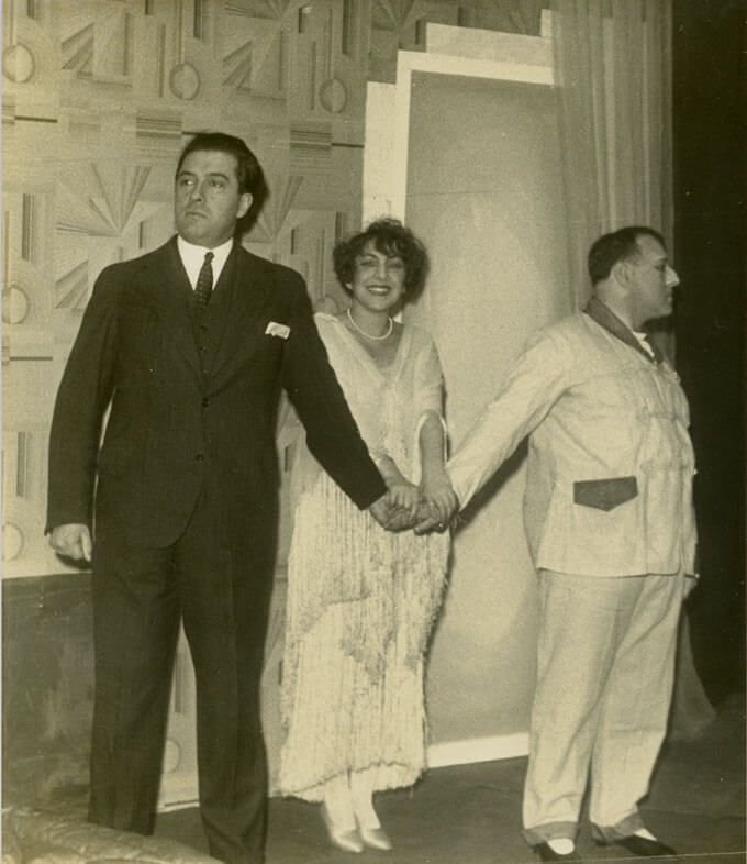 Two men and a women hold their hands together.